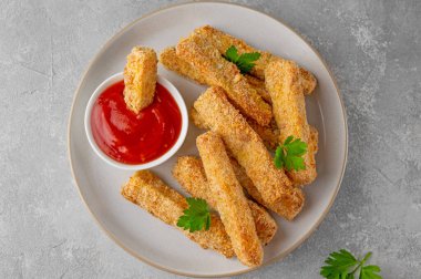 Gri bir arka planda domates sosuyla servis edilen haşlanmış sarımsaklı parmesan kabağı çubukları. Vejetaryen sağlıklı yemek. Seçici odak