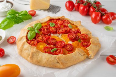 Beyaz ahşap arka planda peynirli domates ya da turta ve otlar. Vejetaryen yemeği. Seçici odak