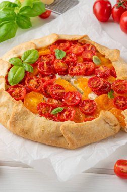 Beyaz ahşap arka planda peynirli domates ya da turta ve otlar. Vejetaryen yemeği. Seçici odak