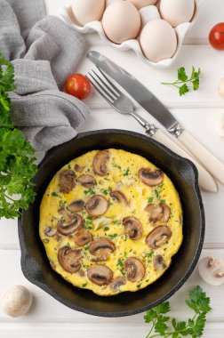 Beyaz ahşap arka planda mantarlı omlet ve tavada otlar. Sağlıklı kahvaltı. Üst Manzara. Boşluğu kopyala