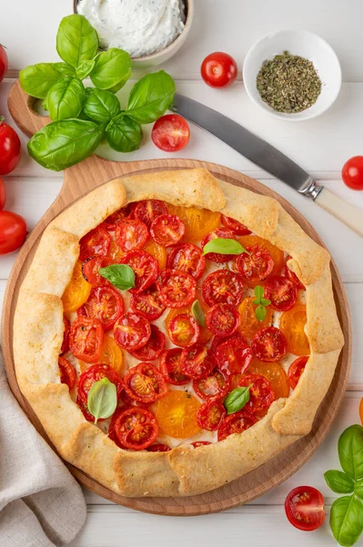 Beyaz ahşap arka planda peynirli domates ya da turta ve otlar. Vejetaryen yemeği. Seçici odak