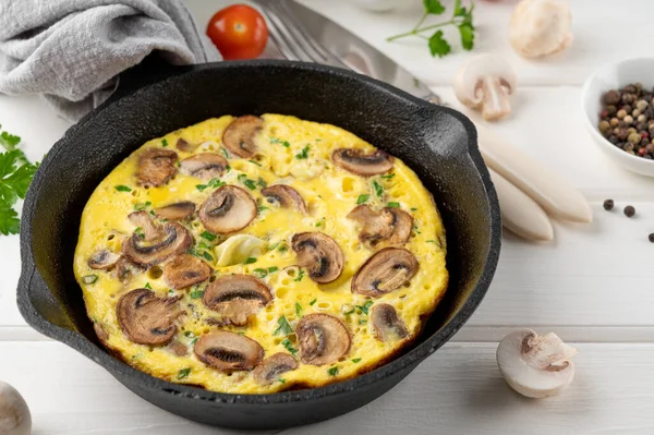 Beyaz ahşap arka planda mantarlı omlet ve tavada otlar. Sağlıklı kahvaltı. Üst Manzara. Boşluğu kopyala