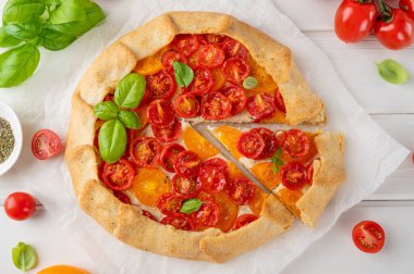 Beyaz ahşap arka planda peynirli domates ya da turta ve otlar. Vejetaryen yemeği. Seçici odak