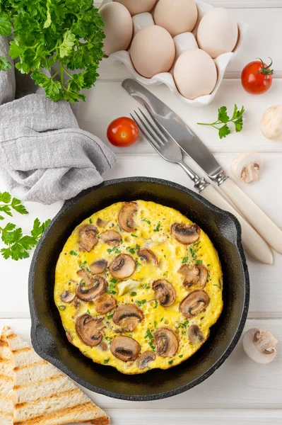 stock image Omelette with mushrooms and herbs in a pan on a white wooden background. Healthy breakfast. Top view. Copy space