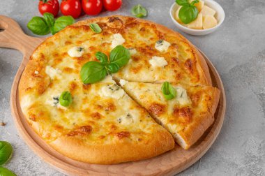 Üzerinde taze fesleğen olan dört peynirli pizza tahta üzerinde gri beton arka plan. Üst görünüm, alanı kopyala.