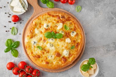 Üzerinde taze fesleğen olan dört peynirli pizza tahta üzerinde gri beton arka plan. Üst görünüm, alanı kopyala.