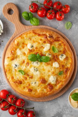 Üzerinde taze fesleğen olan dört peynirli pizza tahta üzerinde gri beton arka plan. Üst görünüm, alanı kopyala.