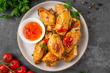 Pişmiş tavuk kanatları, tatlı acı biber sosu ve taze otlarla servis edilir. Seçici odak