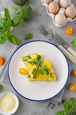 Brokolili omlet, peynir ve gri beton arka planda taze fesleğen. Sağlıklı kahvaltı.