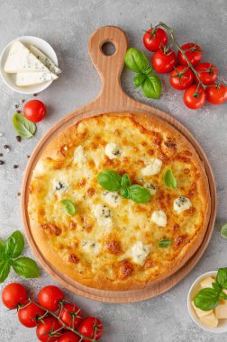 Üzerinde taze fesleğen olan dört peynirli pizza tahta üzerinde gri beton arka plan. Üst görünüm, alanı kopyala.