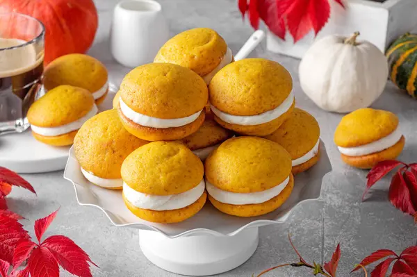 Pumpkin sandwich cookies with cream cheese on a gray concrete bsckground. Spicy autumn dessert. Copy space