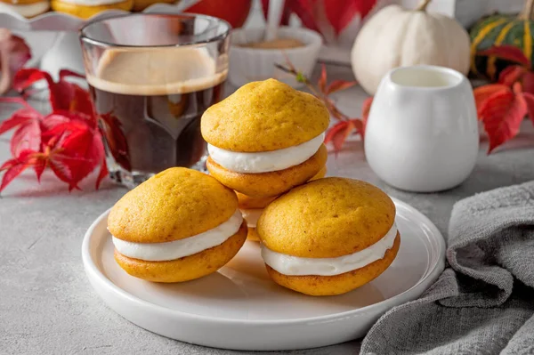 Pumpkin sandwich cookies with cream cheese on a gray concrete bsckground. Spicy autumn dessert. Copy space