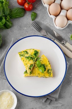 Brokolili omlet, peynir ve gri beton arka planda taze fesleğen. Sağlıklı kahvaltı.