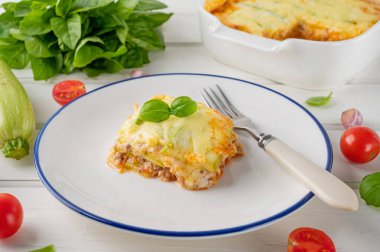 Beyaz ahşap bir zeminde tabak üzerinde sos bolonez soslu lezzetli kabak lazanyası. Sağlıklı yiyecekler. Üst Manzara. Seçici odak