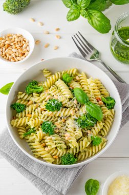 Pesto soslu vejetaryen makarna, brokoli, parmesan peyniri ve beyaz ahşap arka planda çam fıstığı. Sağlıklı yemek.