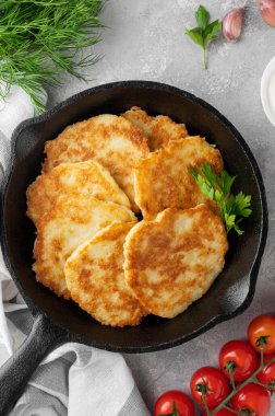 Patates gözlemesi, latke ya da taze otlu draniki ve gri beton arka planda dökme demir bir tavada ekşi krema. Üst görünüm, alanı kopyala