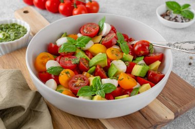 Kiraz domatesli Caprese salatası, mini mozzarella topları, avokado, pesto sosu ve taze fesleğen. Sağlıklı vejetaryen yemeği