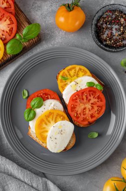 Çavdar ekmeği, domates, mozzarella ve çimento kaplı gri bir tabakta taze fesleğen. Sağlıklı yemek.