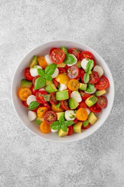 Kiraz domatesli Caprese salatası, mini mozzarella topları, avokado, pesto sosu ve taze fesleğen. Sağlıklı vejetaryen yemeği