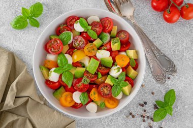 Kiraz domatesli Caprese salatası, mini mozzarella topları, avokado, pesto sosu ve taze fesleğen. Sağlıklı vejetaryen yemeği