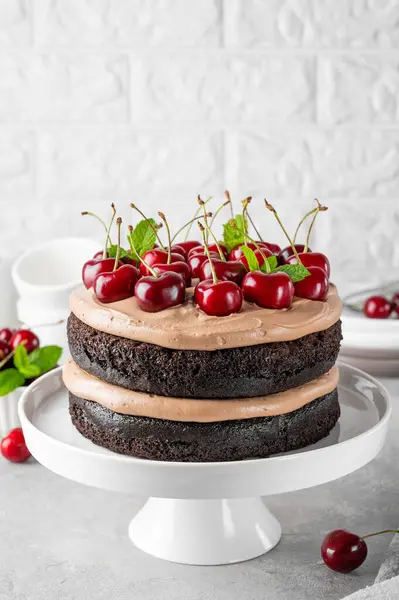Naked Black forest cake, Schwarzwald pie. Cake with dark chocolate, cream and cherry on a gray concrete background. Copy space.
