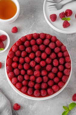 Fırında ahududu peynirli kek ya da jöleli ahududu kremalı kremalı pasta ve gri beton arka planda beyaz bir tabakta taze böğürtlen yok. Yaz pastası
