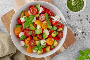 Kiraz domatesli Caprese salatası, mini mozzarella topları, avokado, pesto sosu ve taze fesleğen. Sağlıklı vejetaryen yemeği