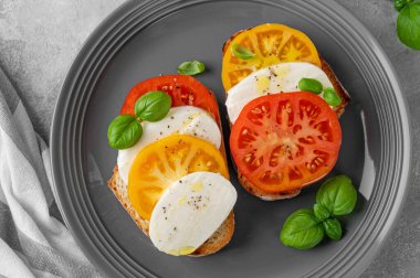 Çavdar ekmeği, domates, mozzarella ve çimento kaplı gri bir tabakta taze fesleğen. Sağlıklı yemek.