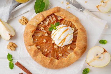 Armut, dondurma, ceviz, karamel sosu ve beyaz ahşap arka planda tarçınlı sonbahar galeti.