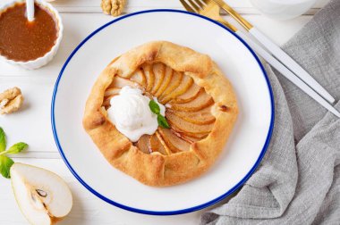 Armut, dondurma, ceviz, karamel sosu ve beyaz ahşap arka planda tarçınlı sonbahar galeti.