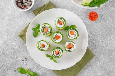 Salatalıklar krem peynirli rulo salatalık, tuzlu somon ve çimento kaplı beyaz bir tabakta servis edilen taze otlar. Seçici odak