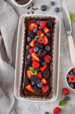 Taze böğürtlenli çikolatalı tart ve gri arka plandaki tabağın üstünde nane şekeri. Yaz tatlısı. Boşluğu kopyala