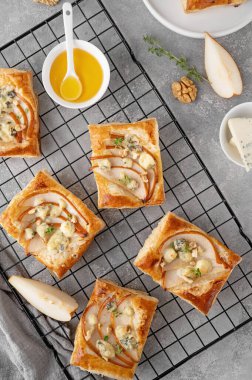 Mini tartlar puf böreği, armut parçaları, mavi peynir, ceviz ve ballı beton zemin. Üst görünüm