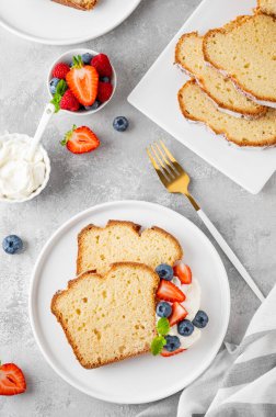 Lezzetli vanilyalı kek, taze böğürtlenler ve gri beton arka planda çırpılmış kremayla servis ediliyor. Seçici odak, boşluğu kopyala