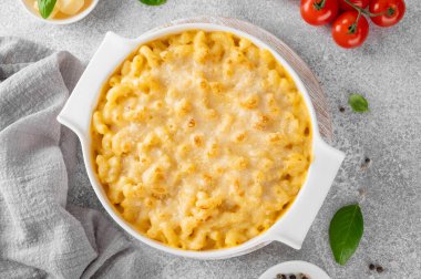 Beyaz bir tencerede, tahta bir tahtanın üzerinde, gri bir beton zeminde makarna ve peynir. Amerikan mutfağı, rahat yemekler. Boşluğu kopyala