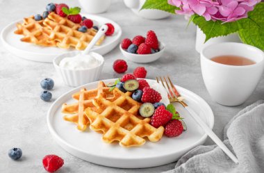 Krem şantili lezzetli Belçika Waffle 'ı, taze böğürtlen ve gri beton arka planda beyaz bir tabakta nane şekeri. Yaz kahvaltısı