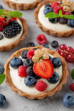 Kremalı, vanilyalı, taze böğürtlenli ve gri arkaplanda nane şekerli tart. Yaz tatlısı