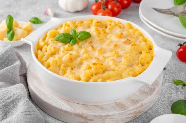 Beyaz bir tencerede, tahta bir tahtanın üzerinde, gri bir beton zeminde makarna ve peynir. Amerikan mutfağı, rahat yemekler. Boşluğu kopyala