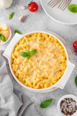 Beyaz bir tencerede, tahta bir tahtanın üzerinde, gri bir beton zeminde makarna ve peynir. Amerikan mutfağı, rahat yemekler. Boşluğu kopyala