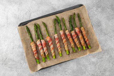 Pastırmaya sarılmış kuşkonmaz ve çimento üzerine rendelenmiş parmesan peyniri serpiştirilmiş. Üst görünüm