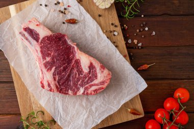 Tahtada çiğ et ve ahşap arka planda pişirmek için malzemeler var. Pirzola. Üst görünüm