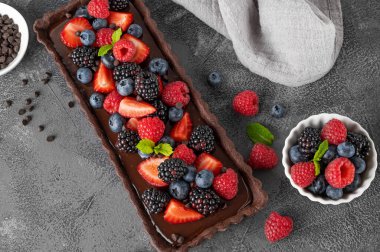 Taze böğürtlenli çikolatalı tart ve koyu arkaplanda nane şekeri. Yaz tatlısı. Boşluğu kopyala