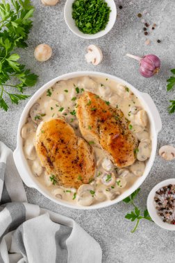 Krema soslu mantarlı kızarmış tavuk göğsü gri beton arka planda beyaz seramik formda. Rahatlatıcı yemek. Üst görünüm