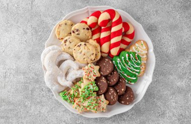 Gri beton arka planda çeşitli ev yapımı Noel kurabiyeleri olan bir tabak. Kutlama yemeği. Üst görünüm, alanı kopyala