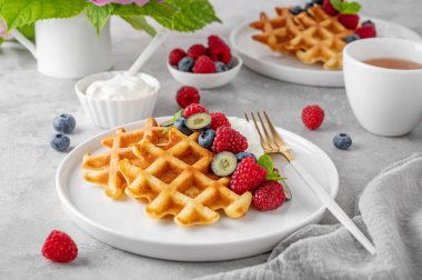 Krem şantili lezzetli Belçika Waffle 'ı, taze böğürtlen ve gri beton arka planda beyaz bir tabakta nane şekeri. Yaz kahvaltısı