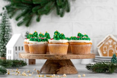 Noel ağacı ve çelenk şeklinde kekler ve üzerine şeker serpiştirilmiş. Hafif beton arka planda Noel tatlısı