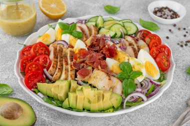 Kızarmış tavuk göğsü, doğranmış avokado, domates, pastırma, salatalık, haşlanmış yumurta ve yeşil yapraklı sağlıklı Cobb salatası. Üst görünüm