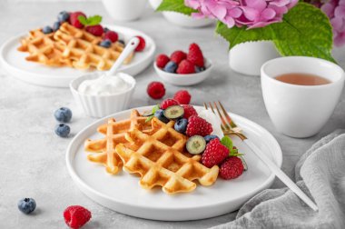 Krem şantili lezzetli Belçika Waffle 'ı, taze böğürtlen ve gri beton arka planda beyaz bir tabakta nane şekeri. Yaz kahvaltısı