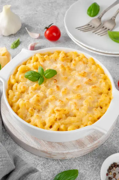 Beyaz bir tencerede, tahta bir tahtanın üzerinde, gri bir beton zeminde makarna ve peynir. Amerikan mutfağı, rahat yemekler. Boşluğu kopyala