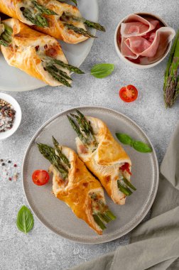 Yeşil kuşkonmazlı fırında puf böreği, prosciutto ya da gri beton arka planda peynirli jambon. Üst görünüm